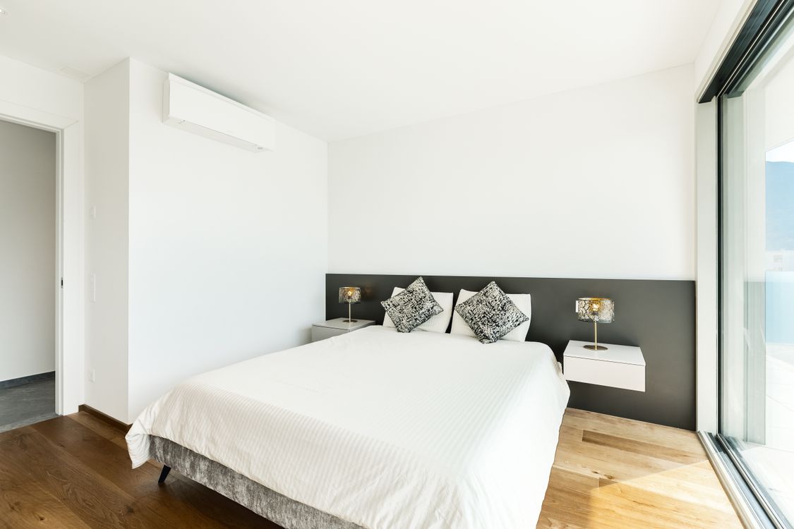 Moderne lichte slaapkamer in Tilburg met wand-gemonteerde split-unit airco boven het bed