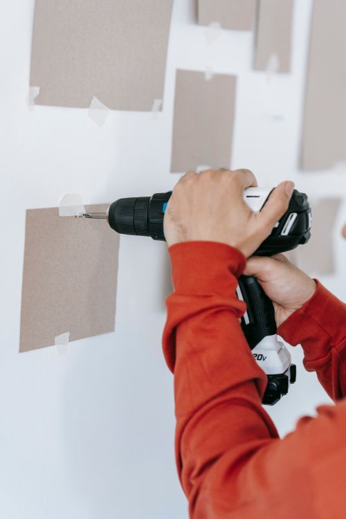 Iemand boort een gat in de muur tijdens de montage van een airco-wandbeugel