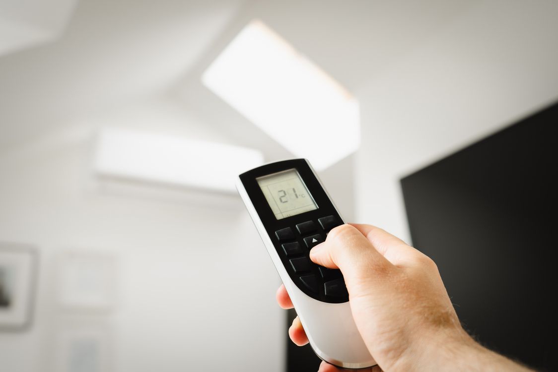 Man bedient zijn airco met een afstandsbediening binnenshuis