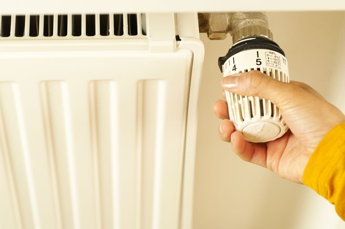 Hand die een radiatorthermostaat instelt om de verwarming te regelen