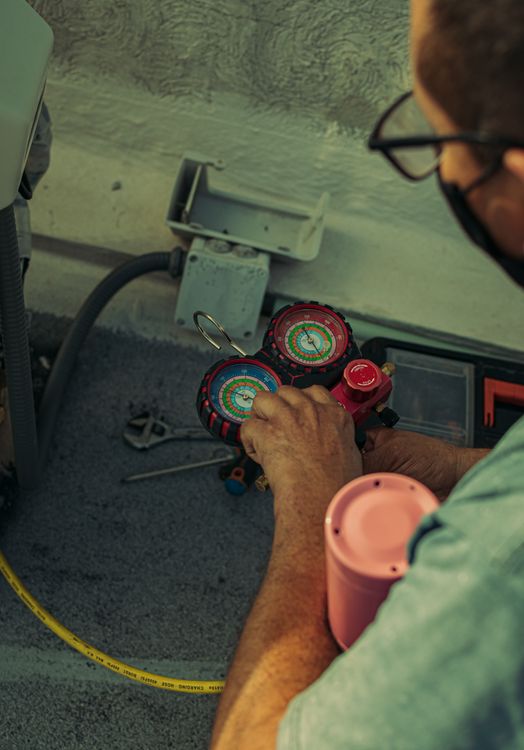 Technicus die een koudemiddelmanometer afleest tijdens airco-onderhoud