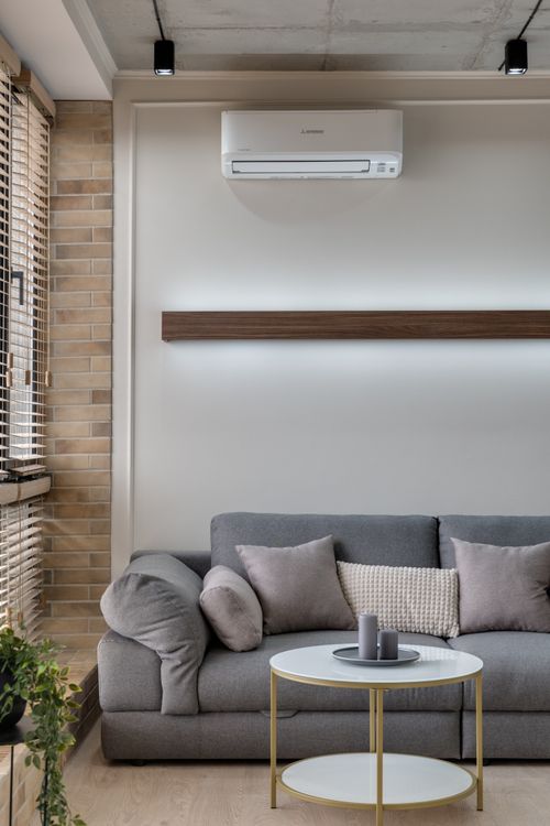 Moderne woonkamer met grijze bank en zichtbare wand-gemonteerde split-unit airco