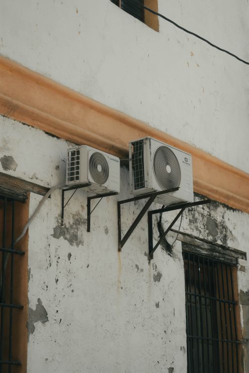 Twee buitenunits van een split-airco gemonteerd aan een betonnen muur